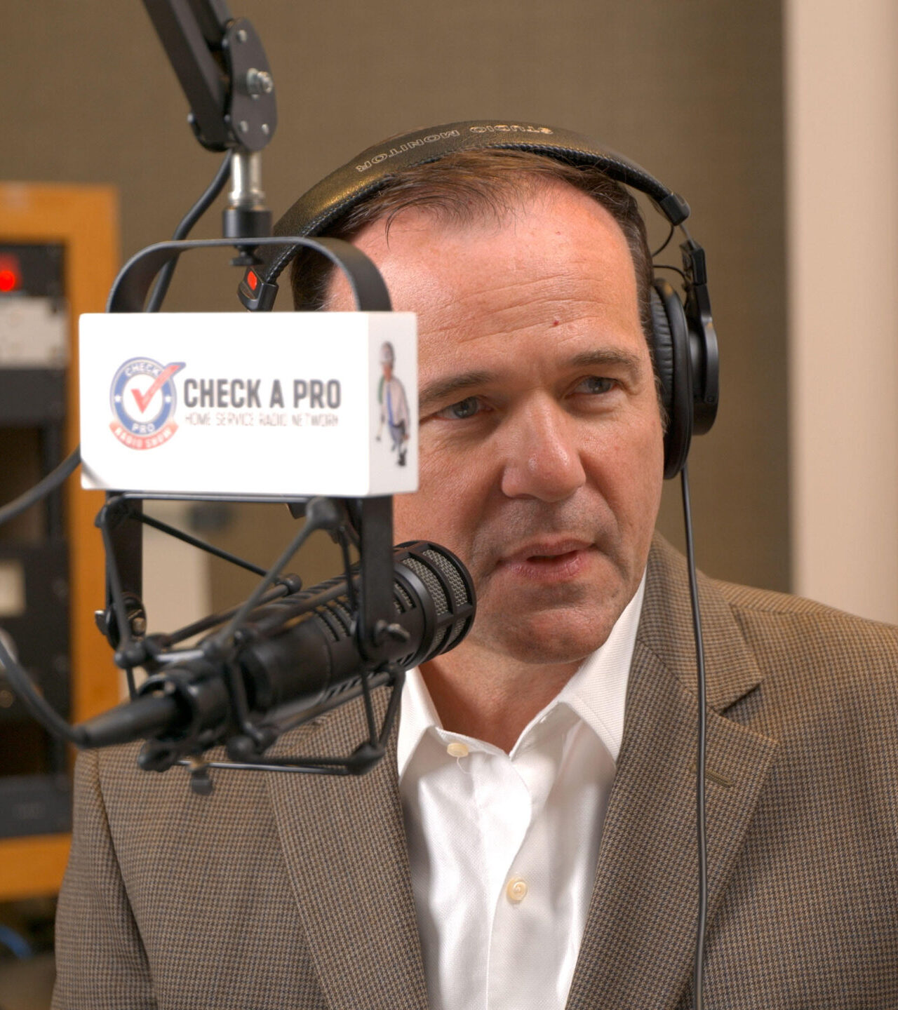 Jim Klauck in the Check A Pro studio with the branded microphone flag